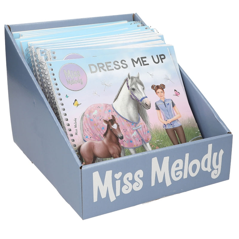 A light blue display box filled with children's books, with the front book titled 'Dress Me Up' and the box labeled 'Miss Melody'.