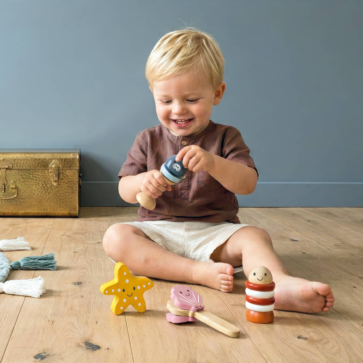 Child playing with toys on a wooden floor against a gray wall