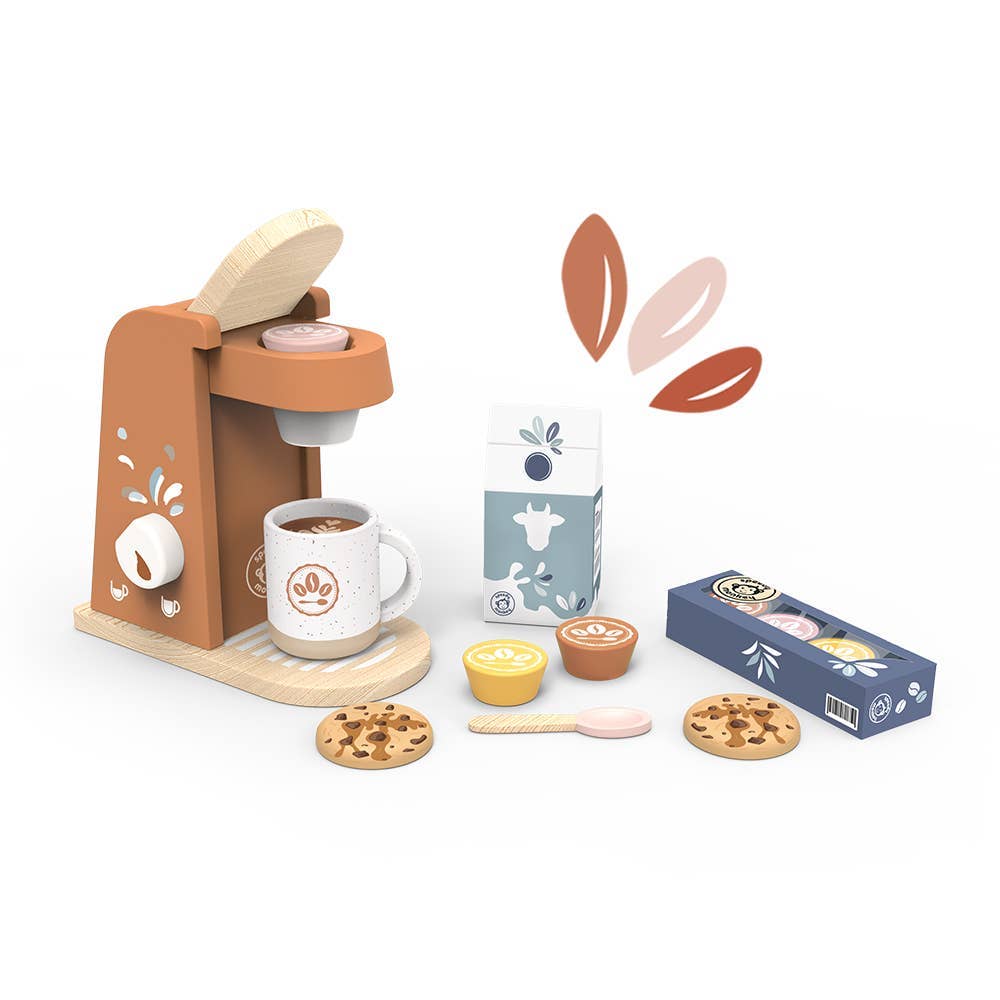 A children's wooden pretend-play coffee set on a white background, including a tan coffee machine, white mug with coffee, milk carton, coffee capsules in a blue box, yellow and brown cups, cookies, a spoon, and floating leaf graphics.